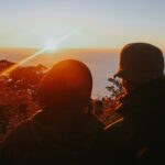 two people on high ground overlooking the sea during sunset