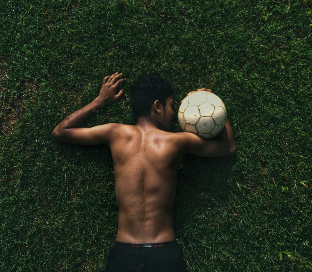 topless man lying on green grass field