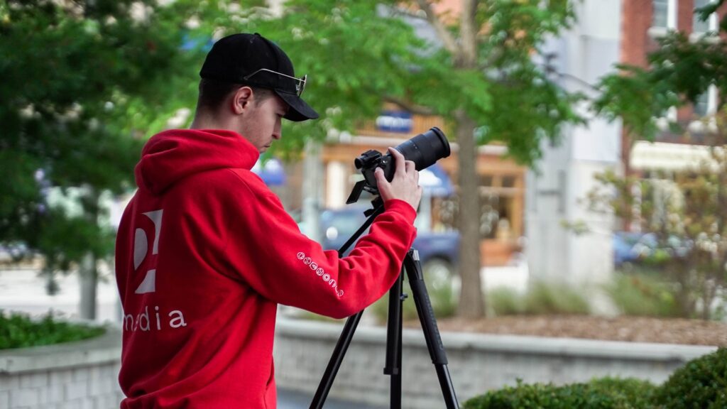 a man in a red hoodie taking a picture with a camera