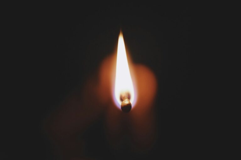 a lit matchstick in the middle of a dark room